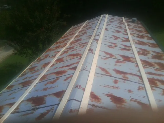 Rusted metal roof panels with new wood purlins before replacement — Storm Damage Roof Repair in Clyman by Roofing Brothers