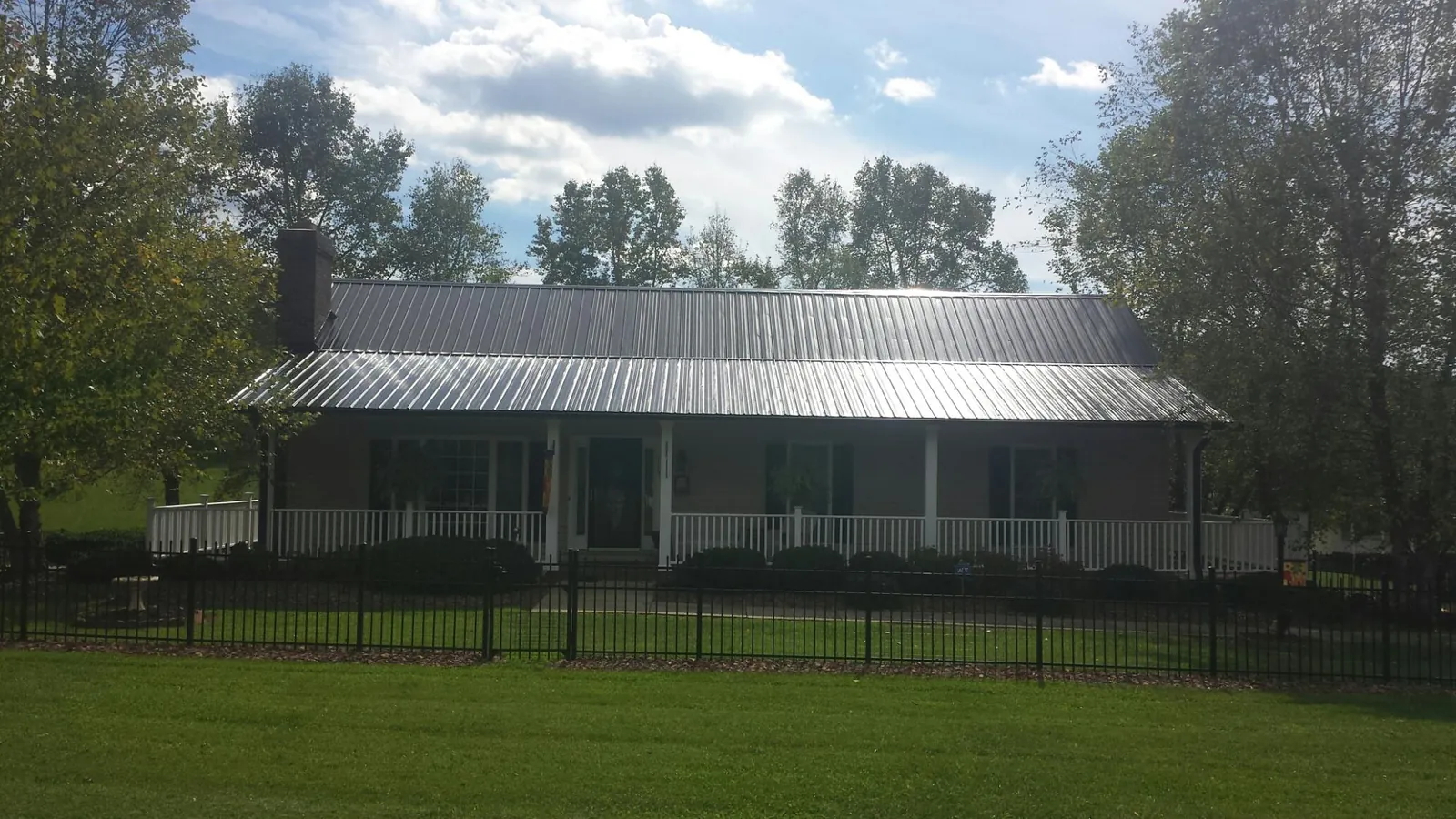 Gray metal roof on a brick ranch with a full width front porch — Gutter Guard Installation work by our crew in Clyman