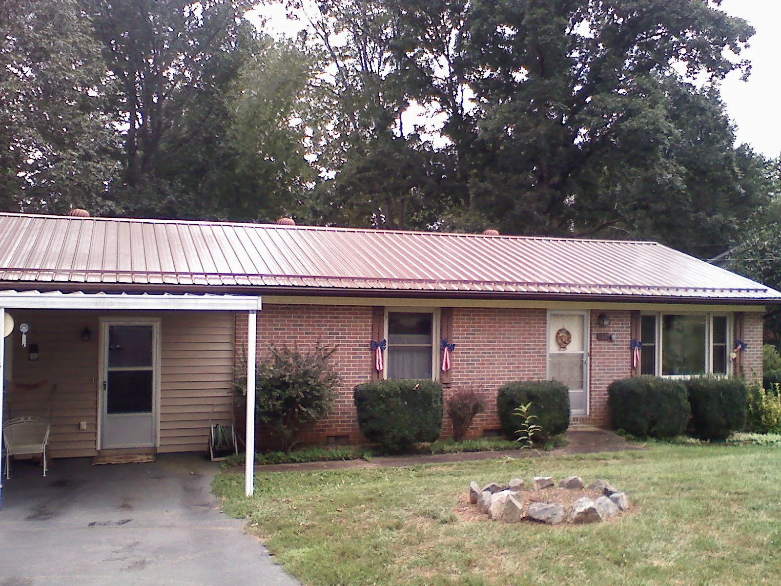 Bronze metal roof and carport on a brick ranch home — Roof Repair work by our crew in Clyman