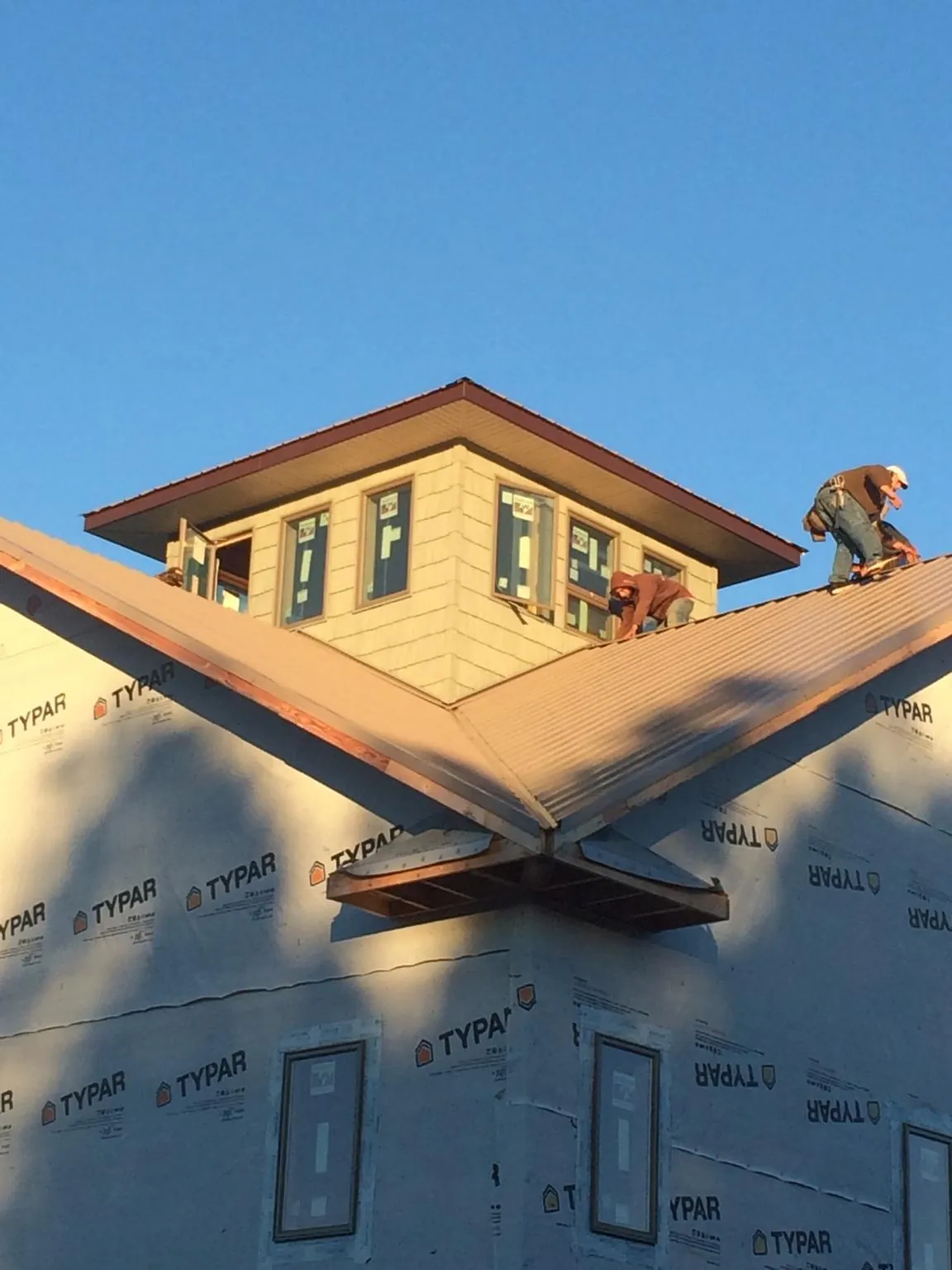 Roofers working around a rooftop cupola on a new metal roof at sunset — Roof Waterproofing in Clyman by Roofing Brothers